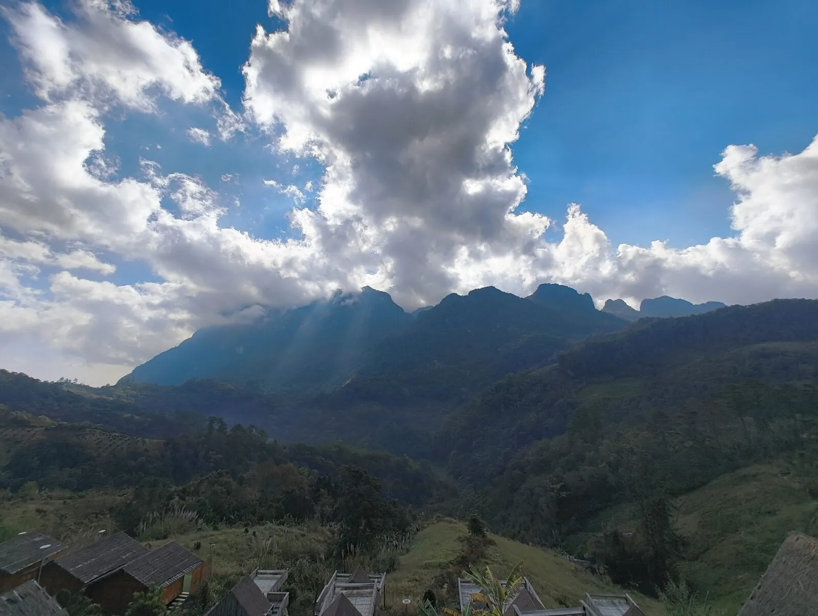Layered mountain ridges under dramatic clouds and sunbeams