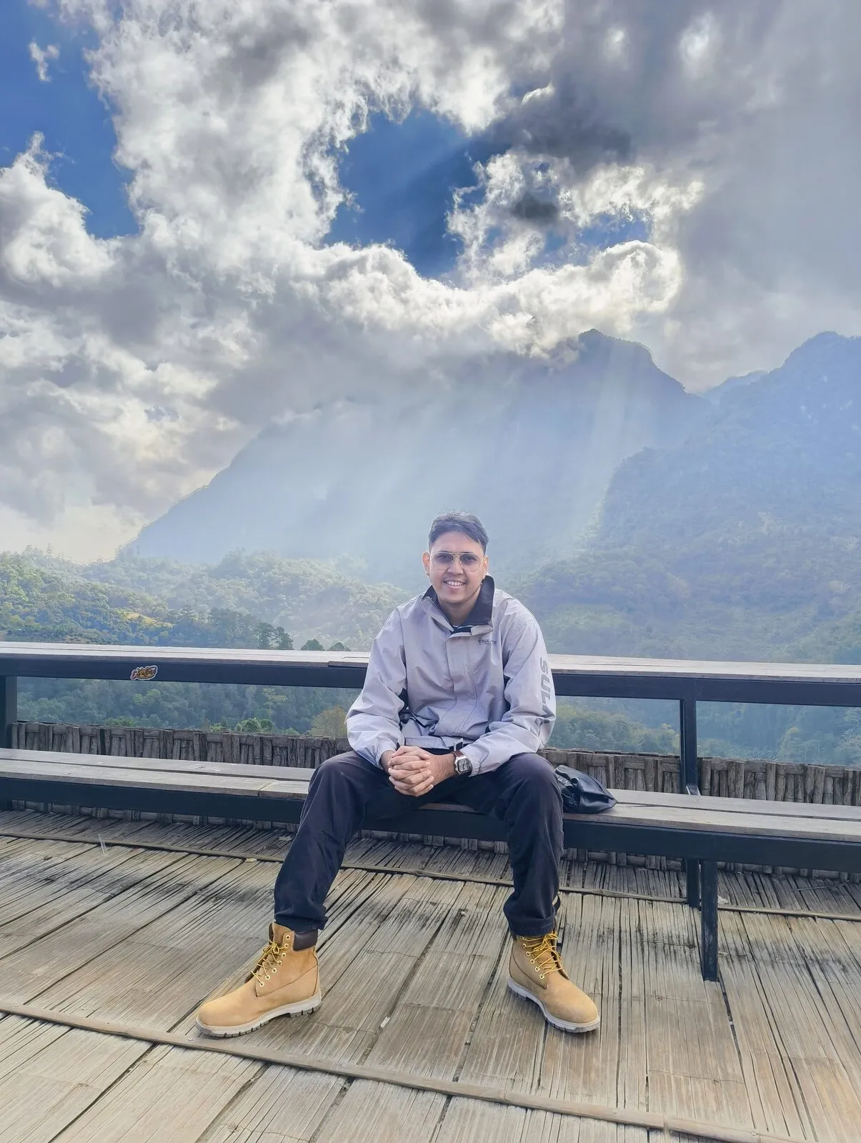 A traveller sitting on a wooden deck with a mountain valley behind him
