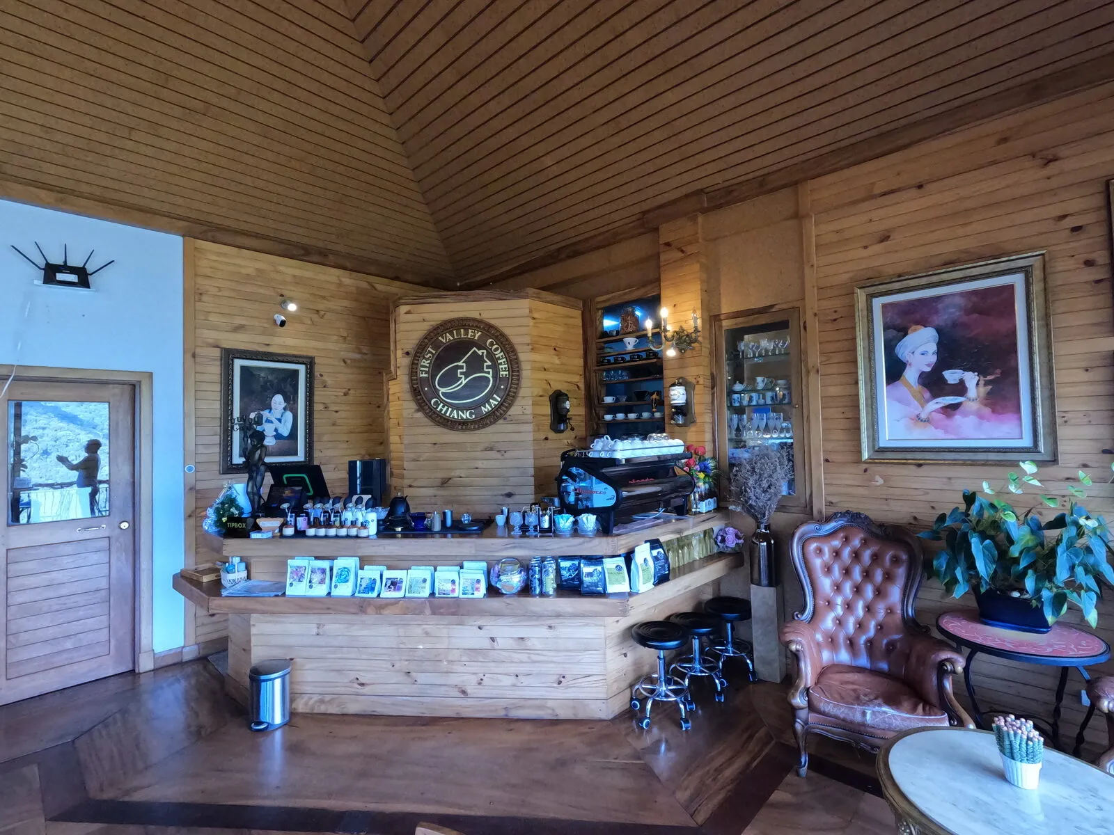 A wooden coffee bar with espresso machines, shelves and framed pictures