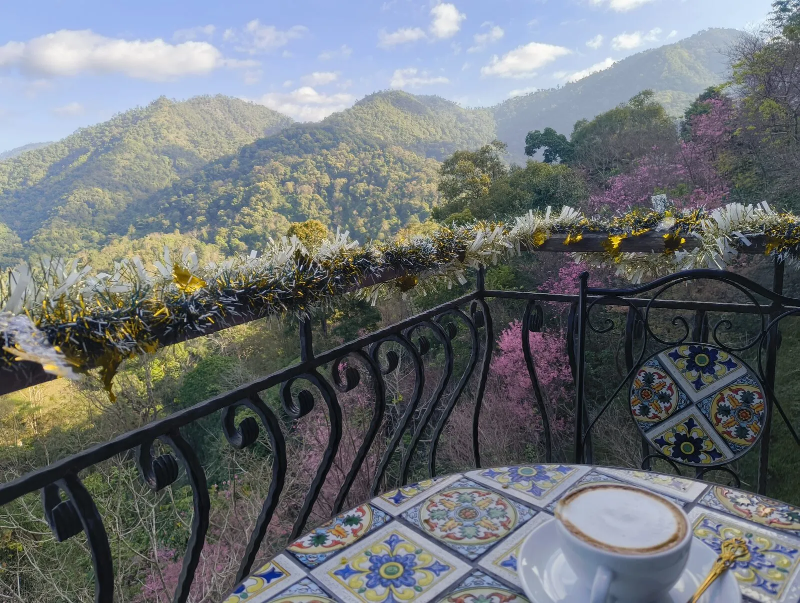 A coffee cup on a tiled table beside a railing, with mountains beyond