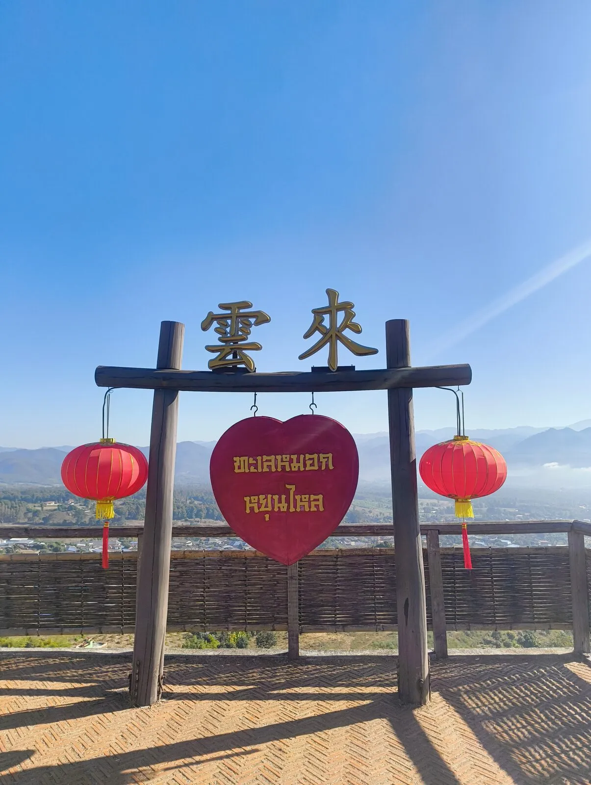 A wooden gate with red lanterns framing a view of the mountains