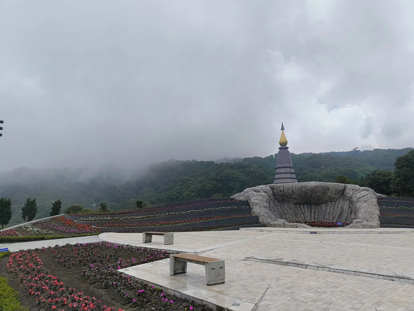 A royal pagoda rising above flower beds in thick fog