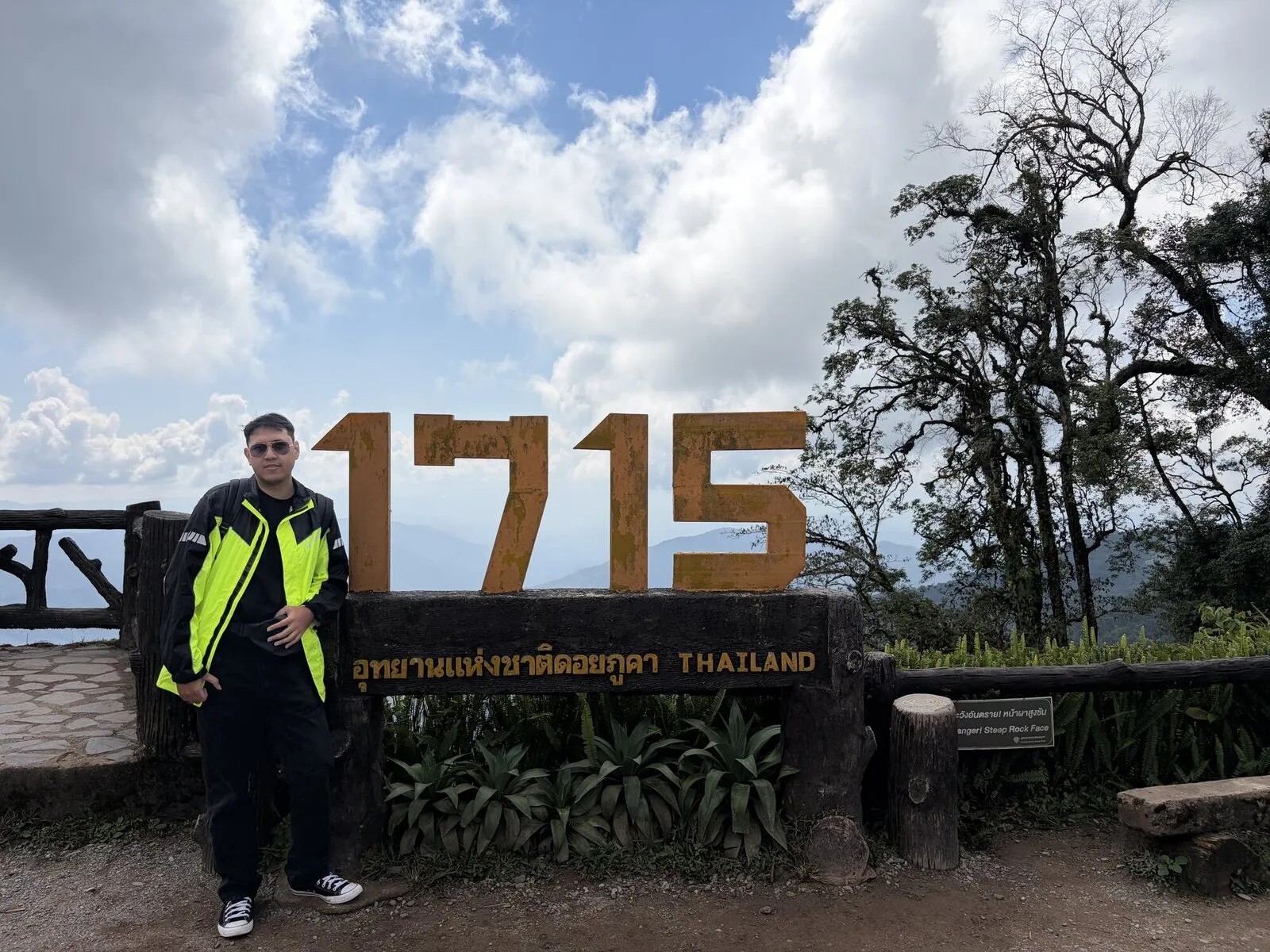 A rider standing beside a large viewpoint sign at 1,715 metres