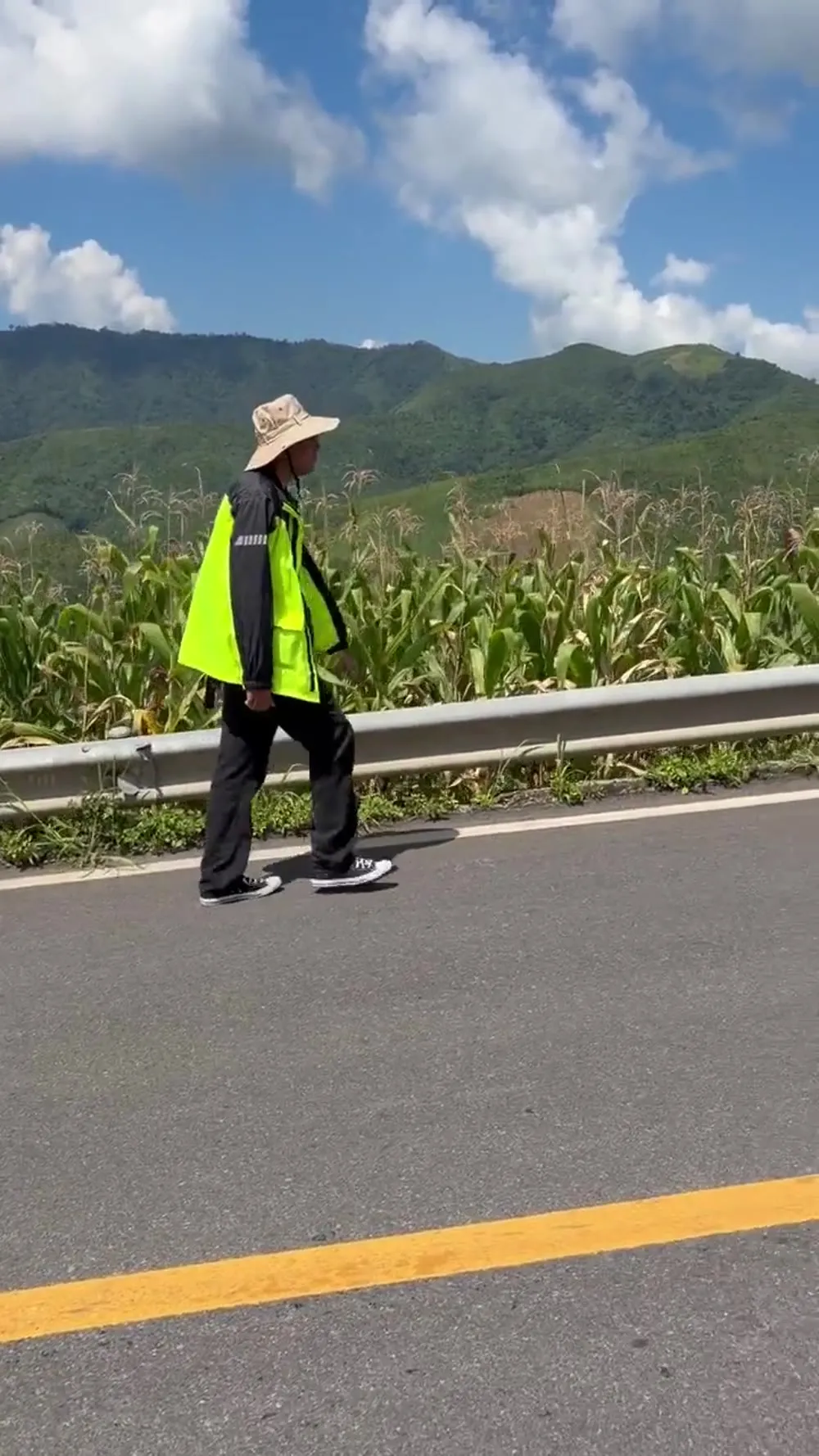 A rider walking beside a cornfield on a mountain road