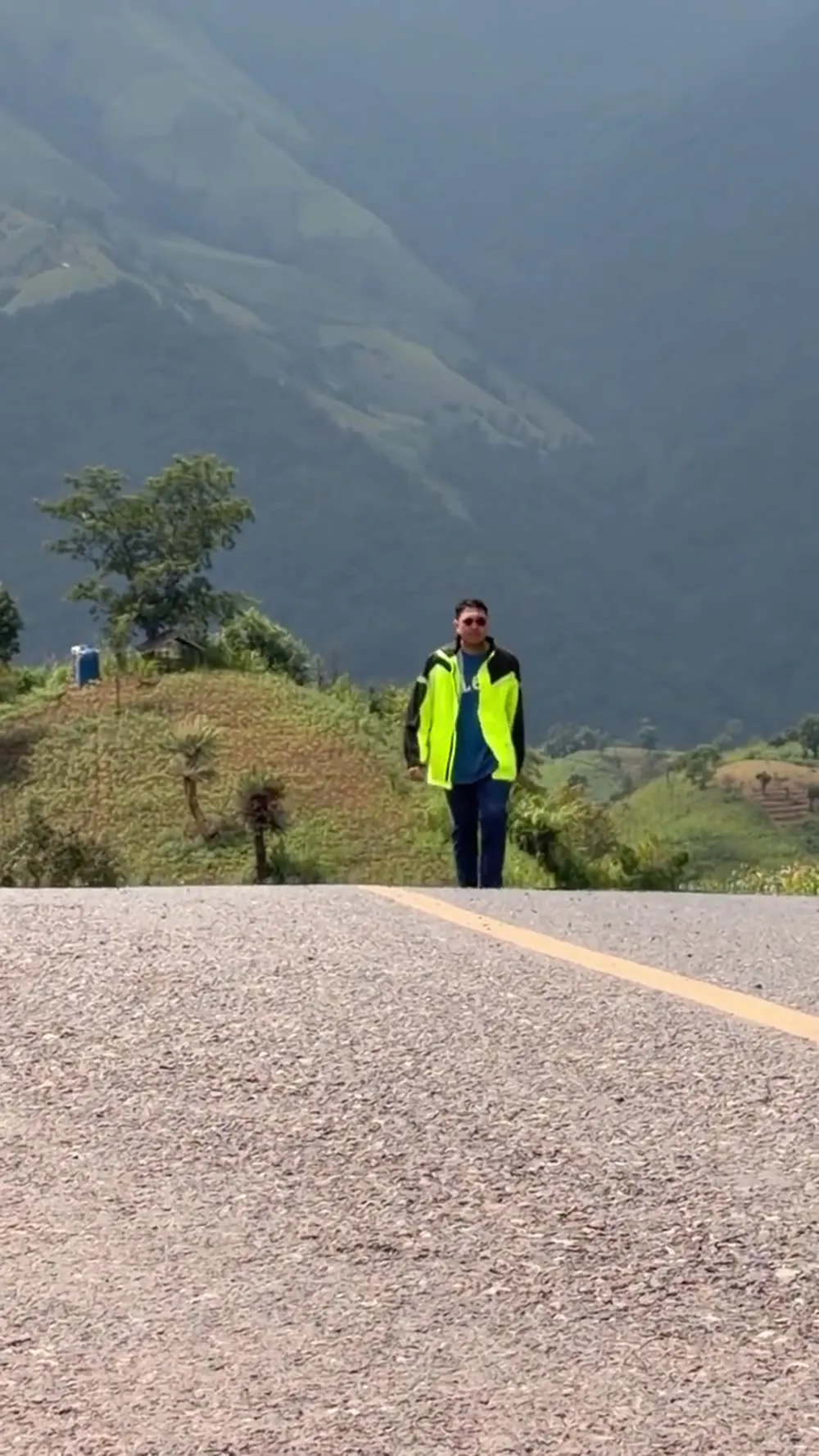 A rider walking along a ridge road beneath green mountains