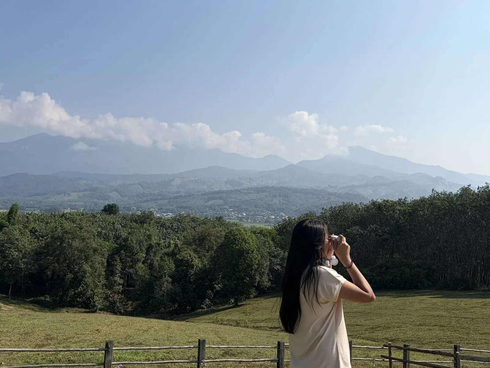 A woman standing in a meadow looking at a mountain valley