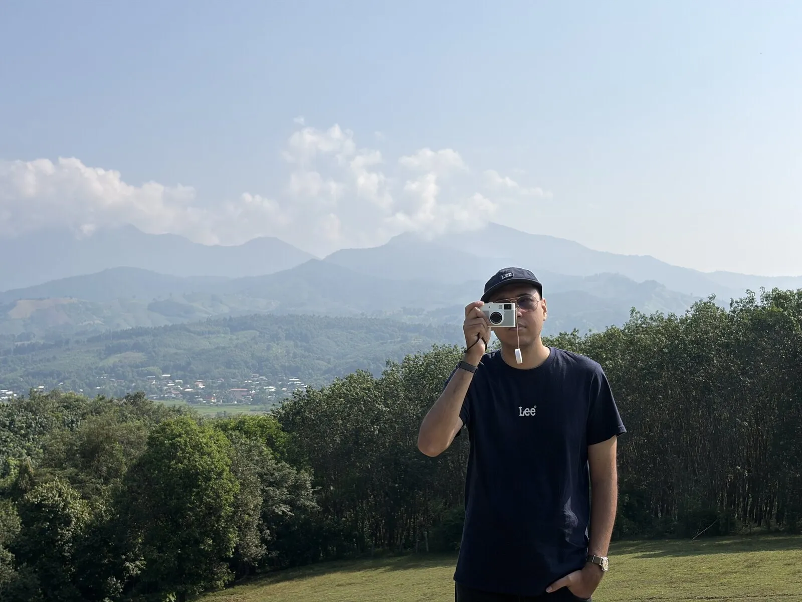 A man in a dark shirt photographing a mountain valley