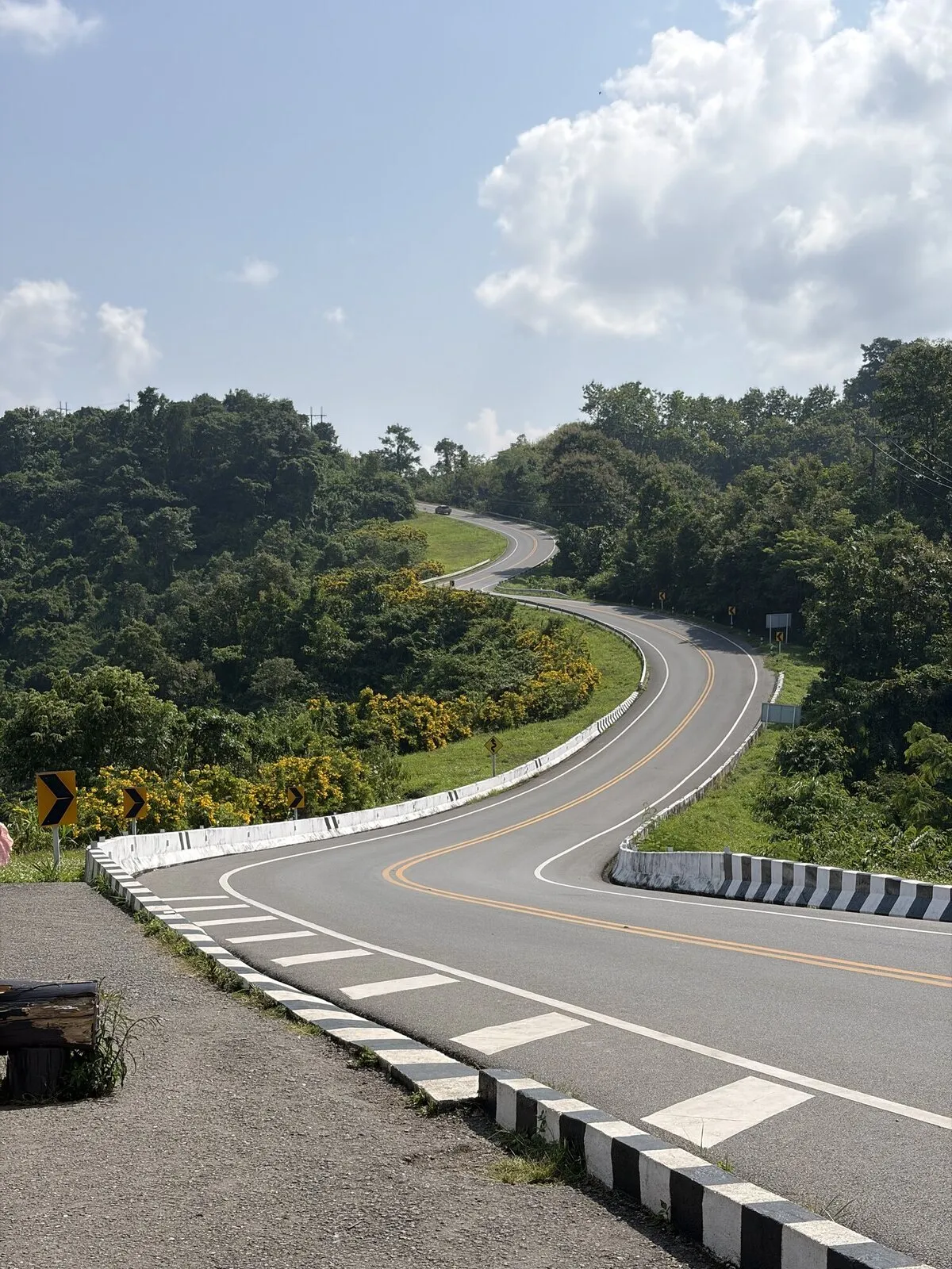 A paved road curving through green hills beneath a cloudy sky