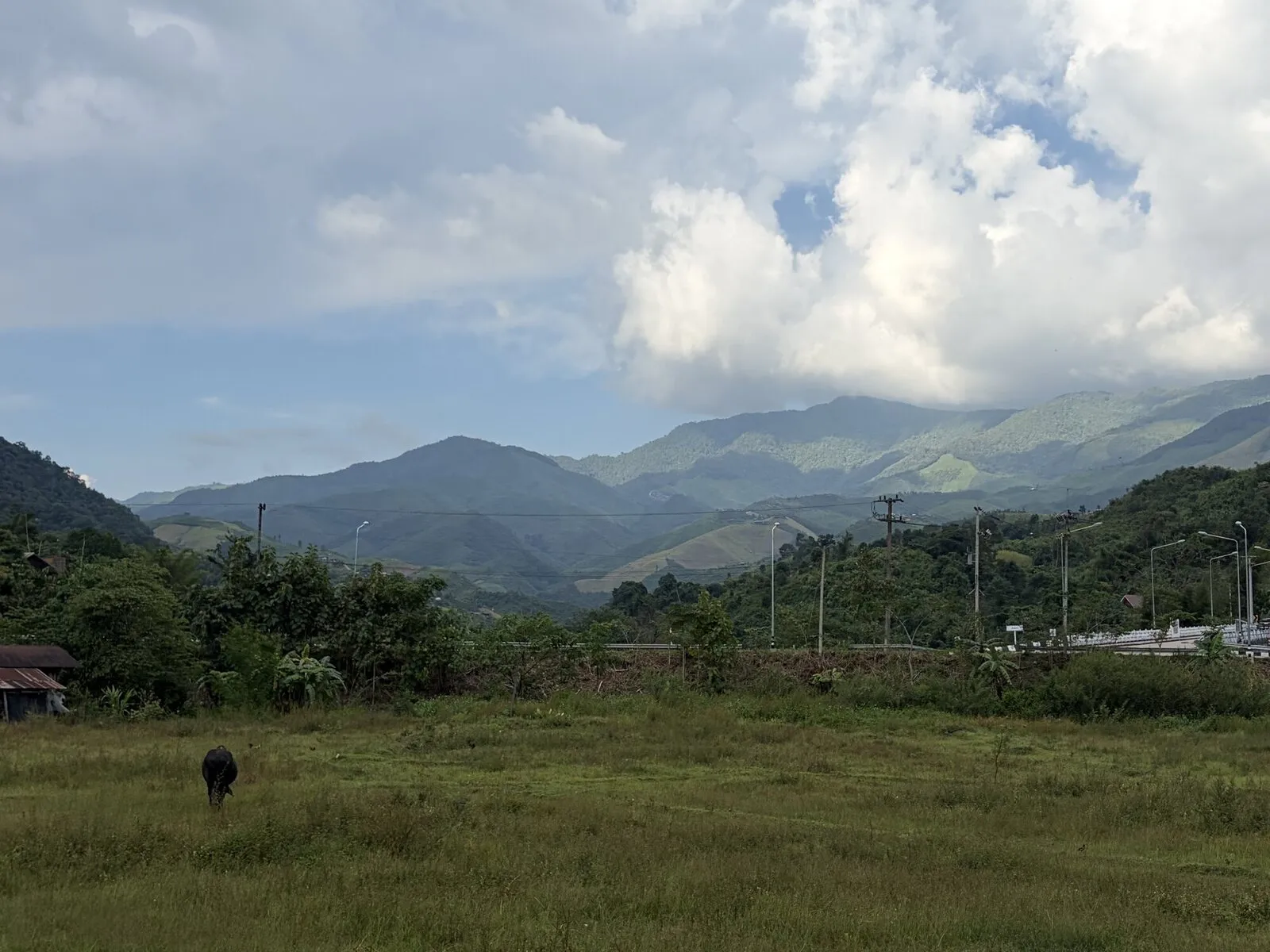 A village in a green valley beneath cloud-covered mountains