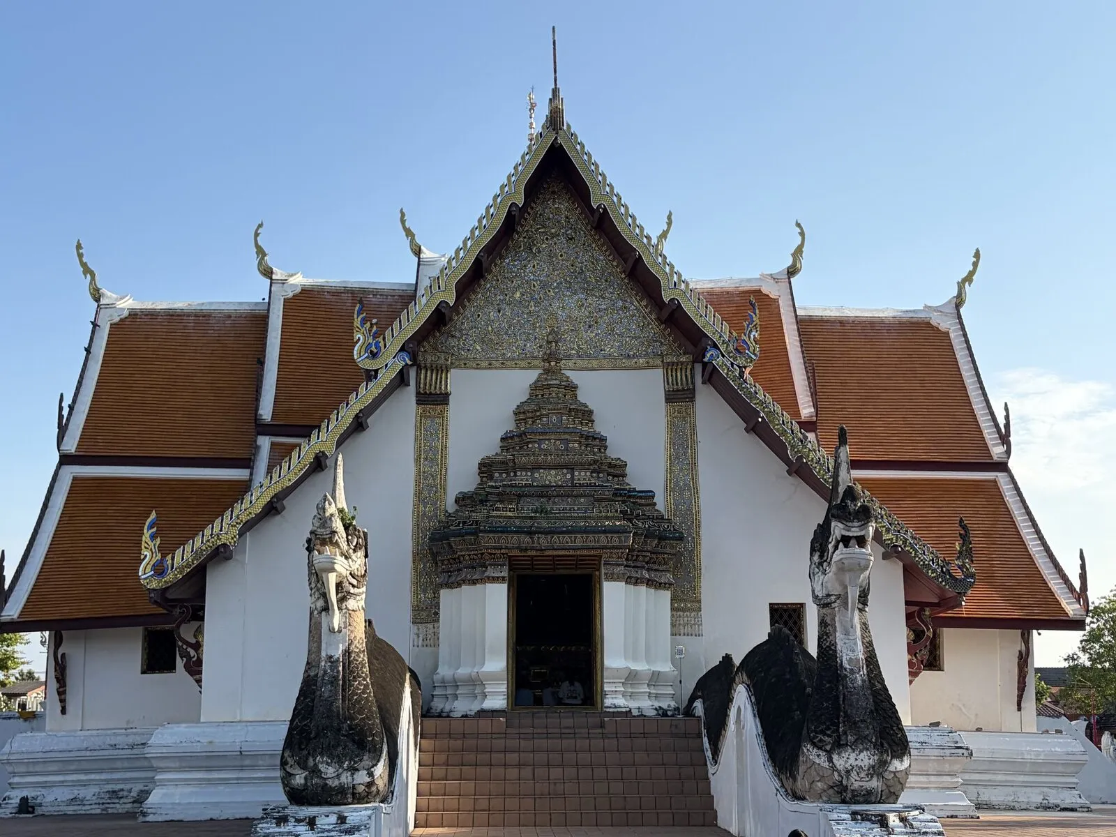 An ornate white temple facade with serpent stairways