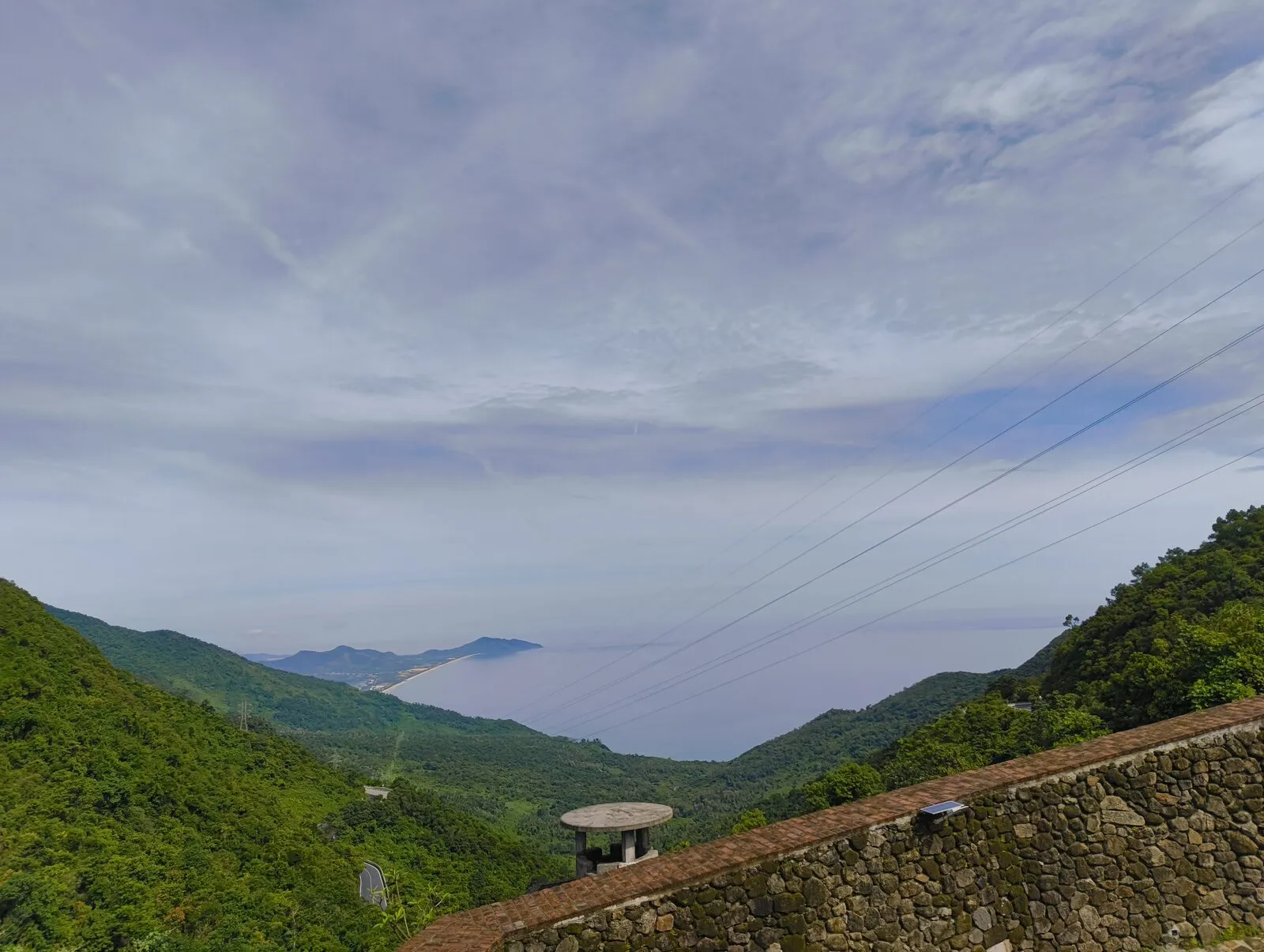 An old stone wall and railing above a green valley